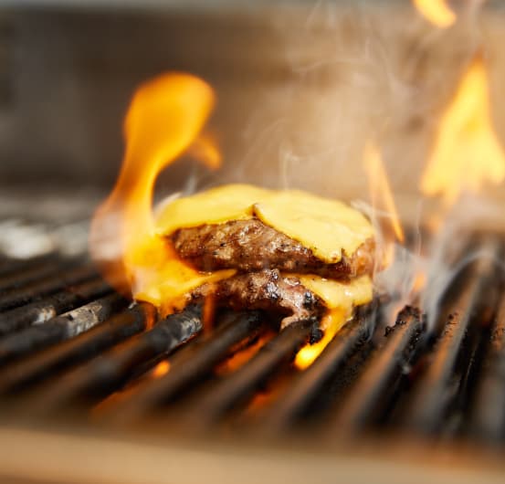 burgers being grilled amongst flames.